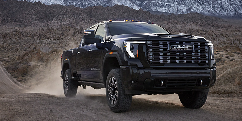 GMC heavy-duty truck driving through rugged mountain terrain.
