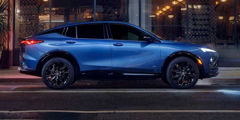 Blue Buick Envista parked on a city street at night.