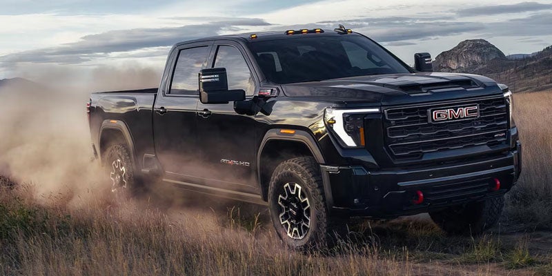 Black GMC Sierra driving through dusty terrain.