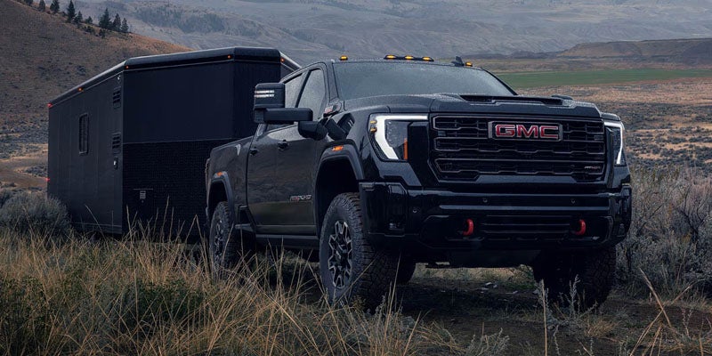 2026 GMC Sierra towing a large trailer across a rugged landscape.